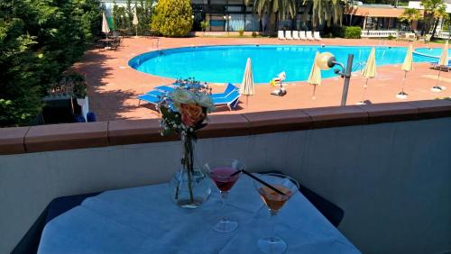 a table with two glasses of wine next to a swimming pool at Hotel Riva Etrusca in Marina di Bibbona