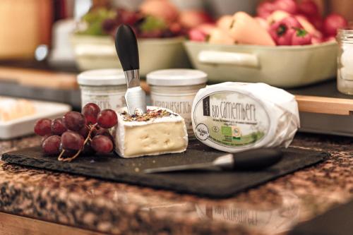 a plate with a piece of cheese and fruit on a counter at GIRLINGGUT Schlafen Starten Salzburg in Elixhausen