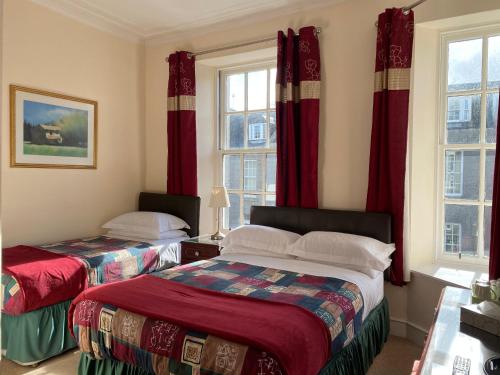 two beds in a room with red curtains at The Royal Crown Guest House in Aberdeen