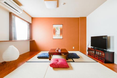 a living room with a table and a tv at GuestHouse MIYABI in Kyoto