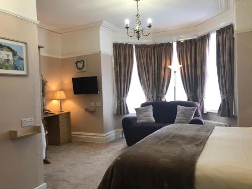 a bedroom with a bed and a chair and a television at Linden Lodge Guest House in Weston-super-Mare