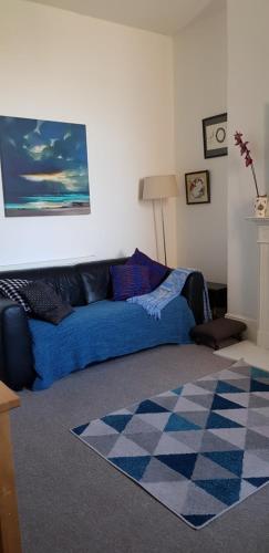 sala de estar con sofá azul y alfombra en Andorinho Sea View Apartment, en Margate