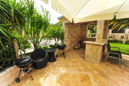 an outdoor patio with an umbrella and a grill at Villa Dolphin Apartments in Petrovac na Moru