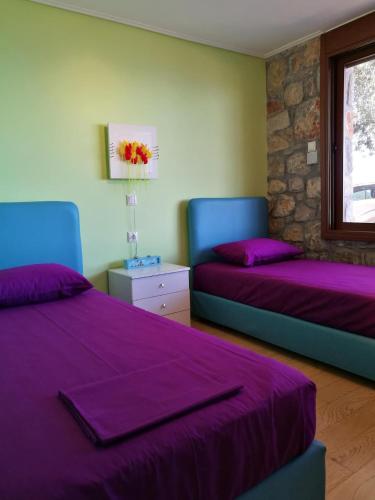 a bedroom with two beds with purple sheets and a window at Villa Thea in Ancient Epidauros