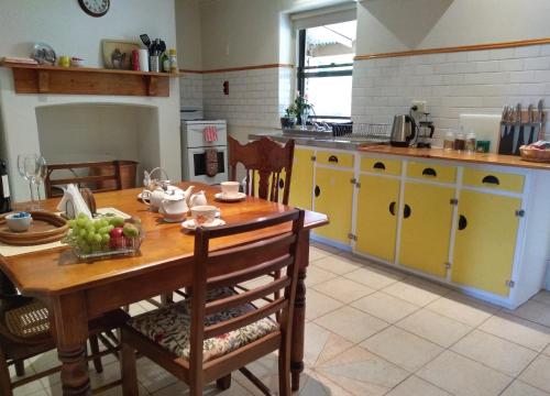 a kitchen with a wooden table and yellow cabinets at Walnut Cottage in Angaston