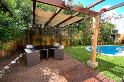 a wooden deck with a pergola next to a pool at Cascais Guincho Beach Villa in Cascais
