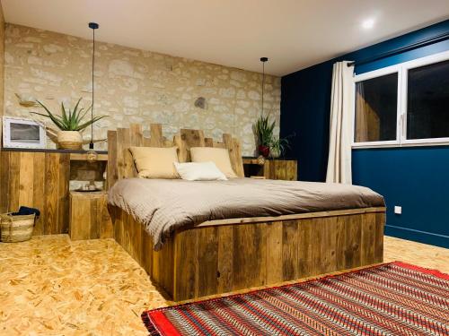 - une chambre avec un lit en bois et un mur bleu dans l'établissement Au bercail de Bizebarre - Maison bois & pierre dans un hameau - Spa, à Saint-Vivien