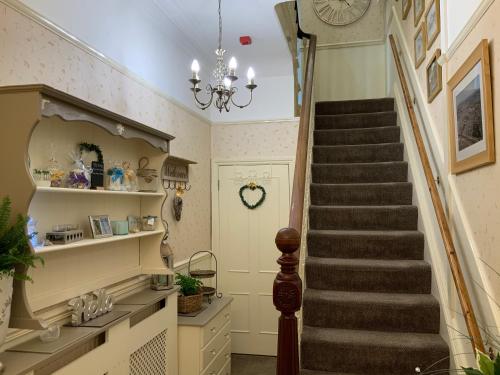 a staircase in a home with a chandelier at Linden Lodge Guest House in Weston-super-Mare