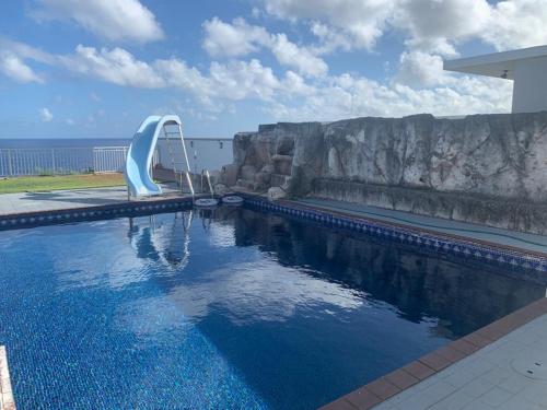 einem Pool mit Rutsche vor dem Meer in der Unterkunft Oceanfront Home with PRIVATE POOL in Tamuning
