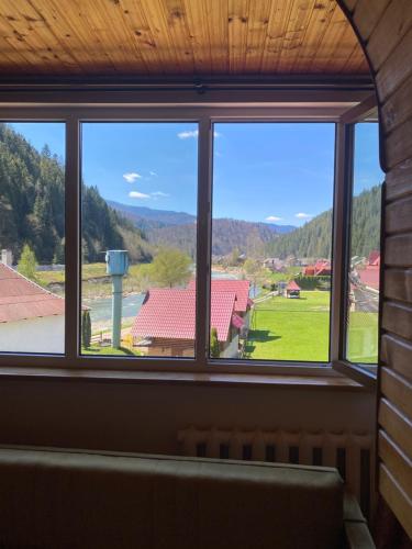 a window with a view of a field and mountains at Садиба "Джерело" in Yaremche