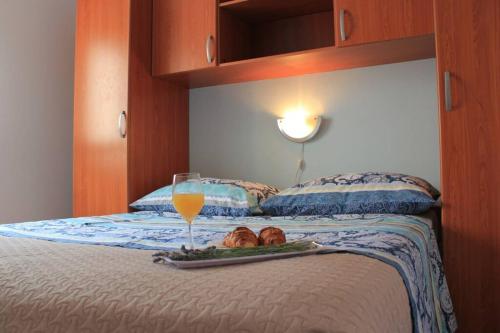 a bed with a tray of bread and a glass of orange juice at Orhideja Apartment in Lukoran