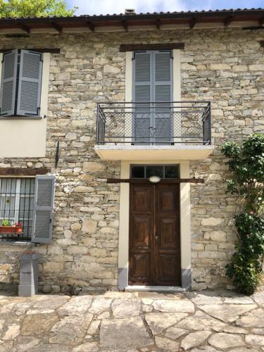 a stone house with a wooden door and a balcony at Cascina Bertolotto Wine Resort in Spigno Monferrato