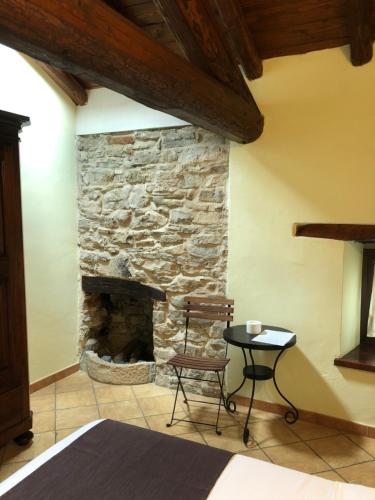 a stone fireplace in a room with a chair and a table at Cascina Bertolotto Wine Resort in Spigno Monferrato
