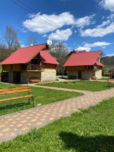 a building with a red roof next to a bench at Садиба "Джерело" in Yaremche