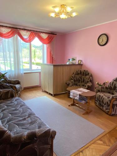 a living room with a couch and a clock on the wall at Садиба "Джерело" in Yaremche