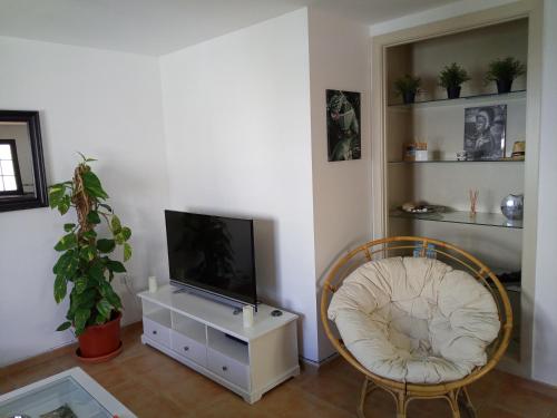 uma sala de estar com uma televisão e uma cadeira em Villa Sunshine em Corralejo