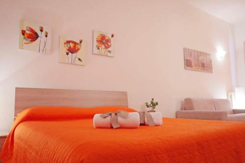 1 dormitorio con 1 cama naranja y 2 toallas en La casa di Giò, en Leverano