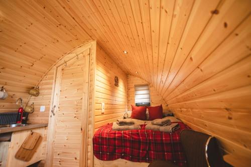 a bedroom in a log cabin with a bed in it at Highland & Transylvania Glamping Pods in Roybridge