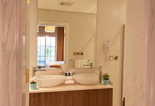 Flamingo Hotel في جدة: حمام به مغسلتين ومرآة كبيرة