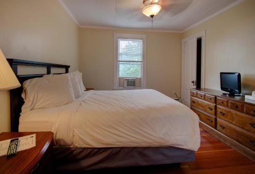 a bedroom with a bed with a television and a dresser at Aspinquid Resort in Ogunquit