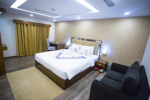a hotel room with a bed and two chairs at Hotel 71 in Dhaka