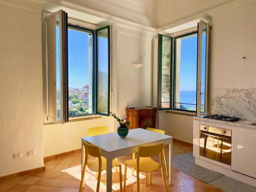 cocina con mesa, sillas y ventanas en Antica Dimora Amalfi Coast, en Scala