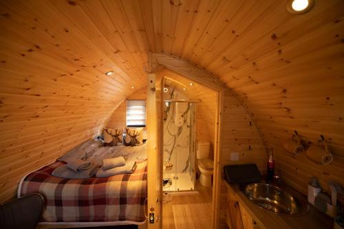 a bedroom in a log cabin with a bed and a sink at Highland & Transylvania Glamping Pods in Roybridge