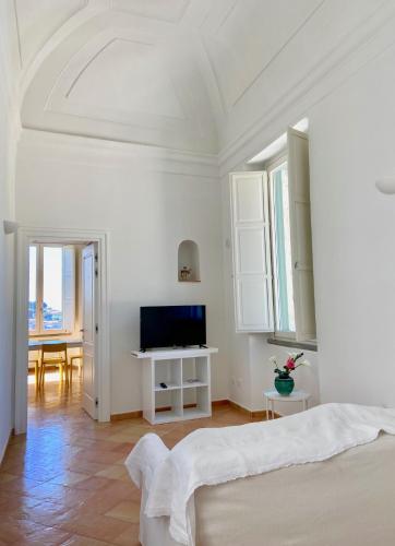 a white bedroom with a bed and a tv at Antica Dimora Amalfi Coast in Scala