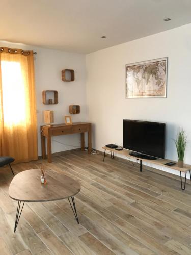 a living room with a flat screen tv and a table at Cottage La Villa Sant Martí in Perpignan