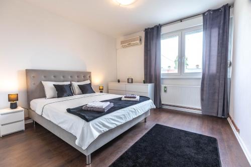 a bedroom with a large bed and a large window at Cosy Apartment Hugo in Osijek
