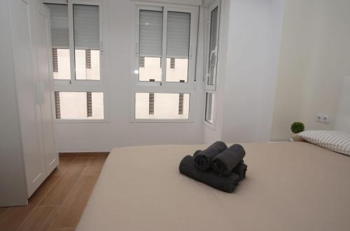 een witte kamer met een zwarte handdoek op de vloer bij Apartamentos Navas GAM in Alicante