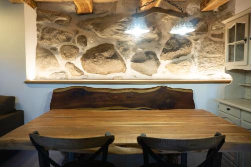 a dining table in a kitchen with a stone wall at Maso Moretto in Pieve Tesino