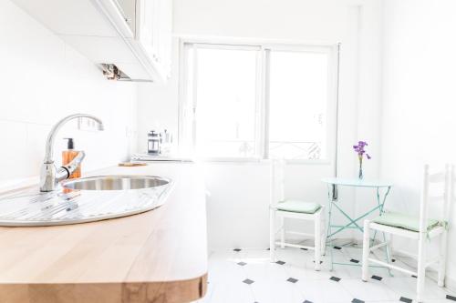 a white kitchen with a sink and a chair at Ama in Estepona