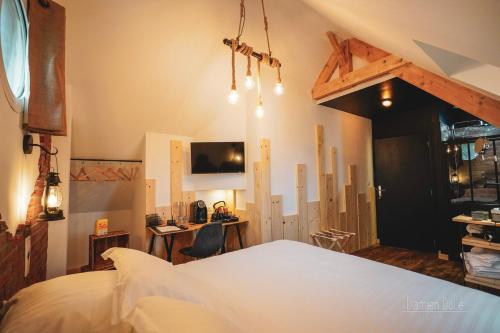 um quarto com uma grande cama branca e uma secretária em Le Saltimbanque - Auberge du Moulin em Eaucourt-sur-Somme