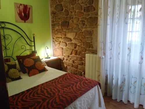 a bedroom with a bed and a stone wall at Casa Rural A Eira Vella in Padrón