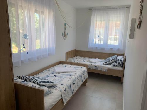 two beds in a room with two windows at APARTMANI SUNSIDE NIN in Nin