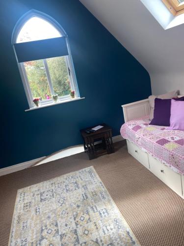 a blue bedroom with a bed and a window at The Willows Lovely Double Apartment in Rostrevor