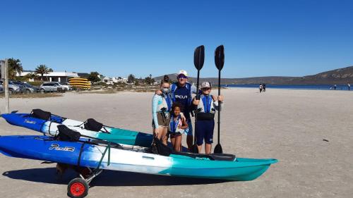 a family standing next to a kayak on the beach at Malindila Apartment & House in Langebaan