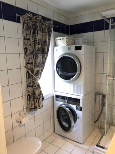 a washer and dryer in a bathroom with a window at Koselig maritim leilighet sentralt i Stavern in Stavern
