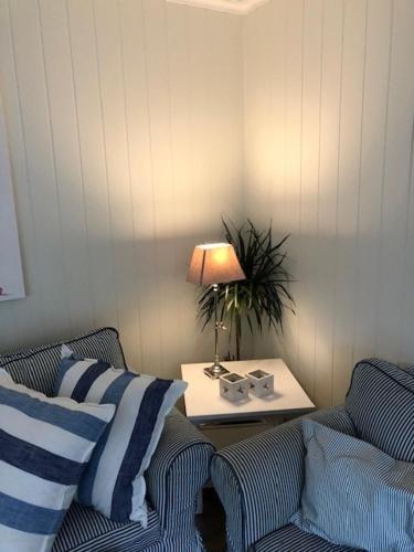 a living room with two couches and a table with a lamp at Koselig maritim leilighet sentralt i Stavern in Stavern