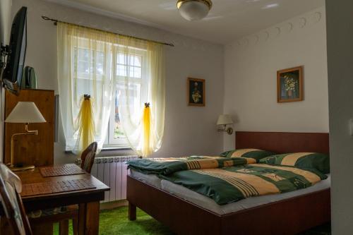 a bedroom with a bed and a desk and a window at Apartamenty i Pokoje Gościnne Salon z kominkiem Dworek Niespodzianka z dużym ogrodem in Szklarska Poręba