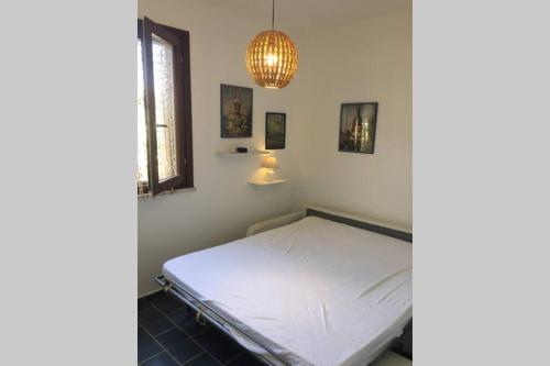 um quarto com uma cama branca e um lustre em Vacanze isolane em Favignana