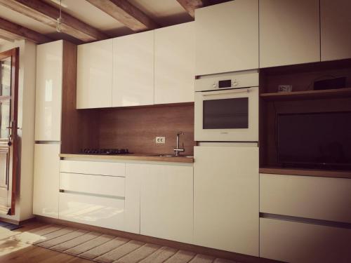 La cuisine est équipée de placards blancs et d'un four micro-ondes. dans l'établissement Apartma Kras, à Komen