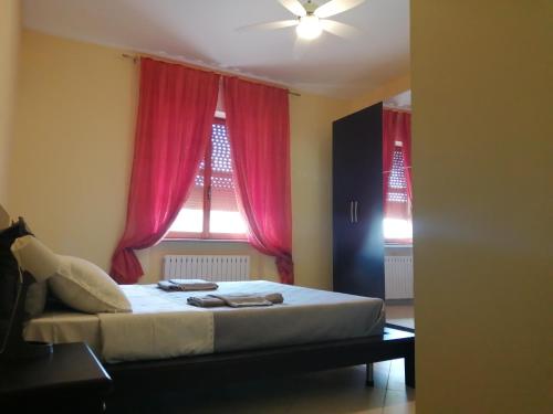 a bedroom with a bed and a window with red curtains at Feriepuntograzia in Porto Potenza Picena