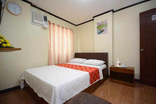 1 dormitorio con 1 cama y reloj en la pared en Isteraha Haven Inn en Zamboanga