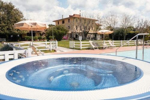 a large swimming pool with a house in the background at Agriturismo Podere L'Agave in San Vincenzo