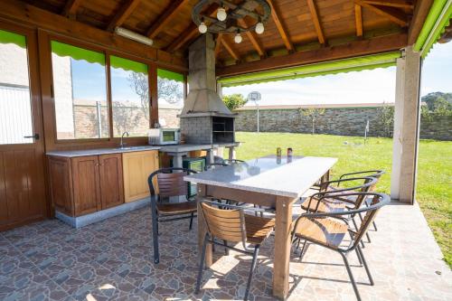 eine Außenküche mit einem Tisch und Stühlen auf einer Terrasse in der Unterkunft El Pinar in Ribadeo