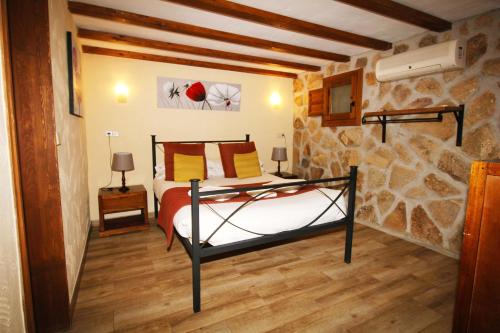1 dormitorio con cama y pared de piedra en Finca El Destino en El Berrueco