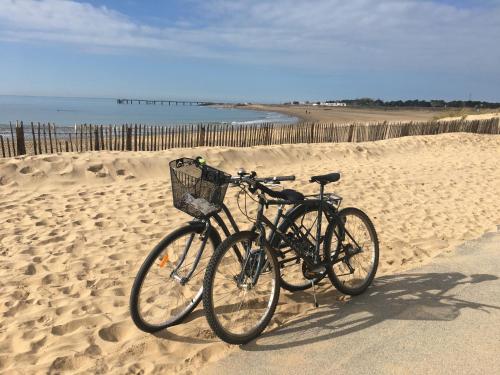 zwei Fahrräder, die am Strand in der Nähe des Ozeans geparkt sind in der Unterkunft Maison de pays à 2 pas de la mer et du centre in La Tranche-sur-Mer