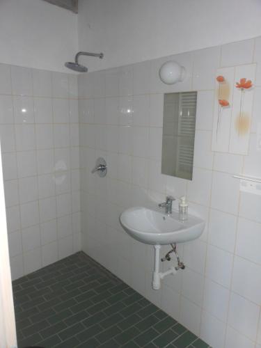 a white bathroom with a sink and a mirror at Merum Pincészet és Vendégszoba in Tállya